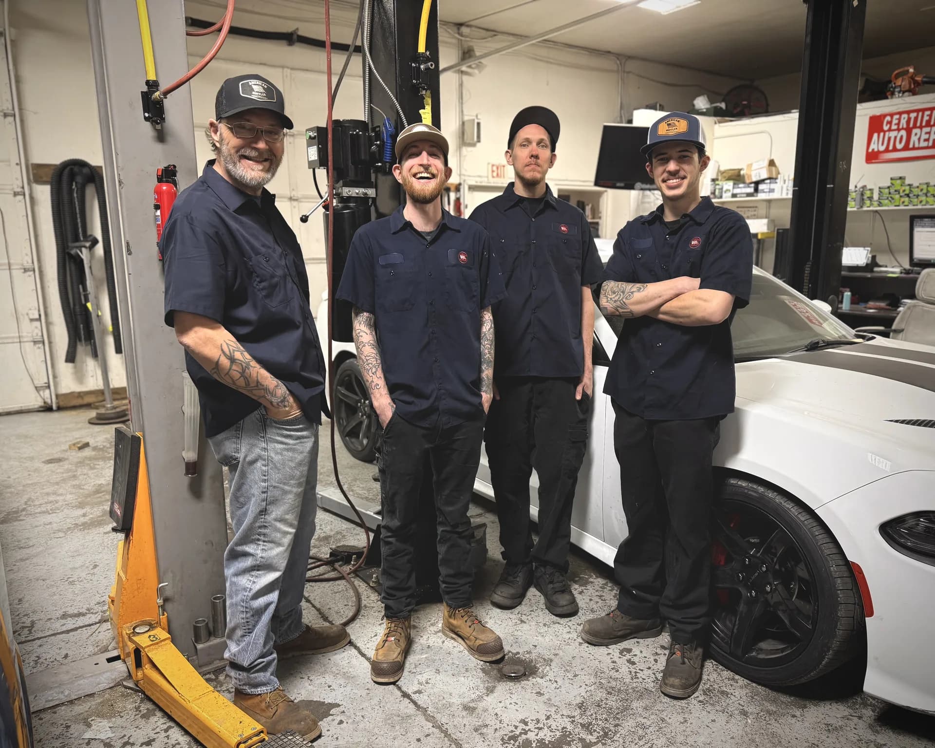 certified auto repair team portrait with sports car in shop