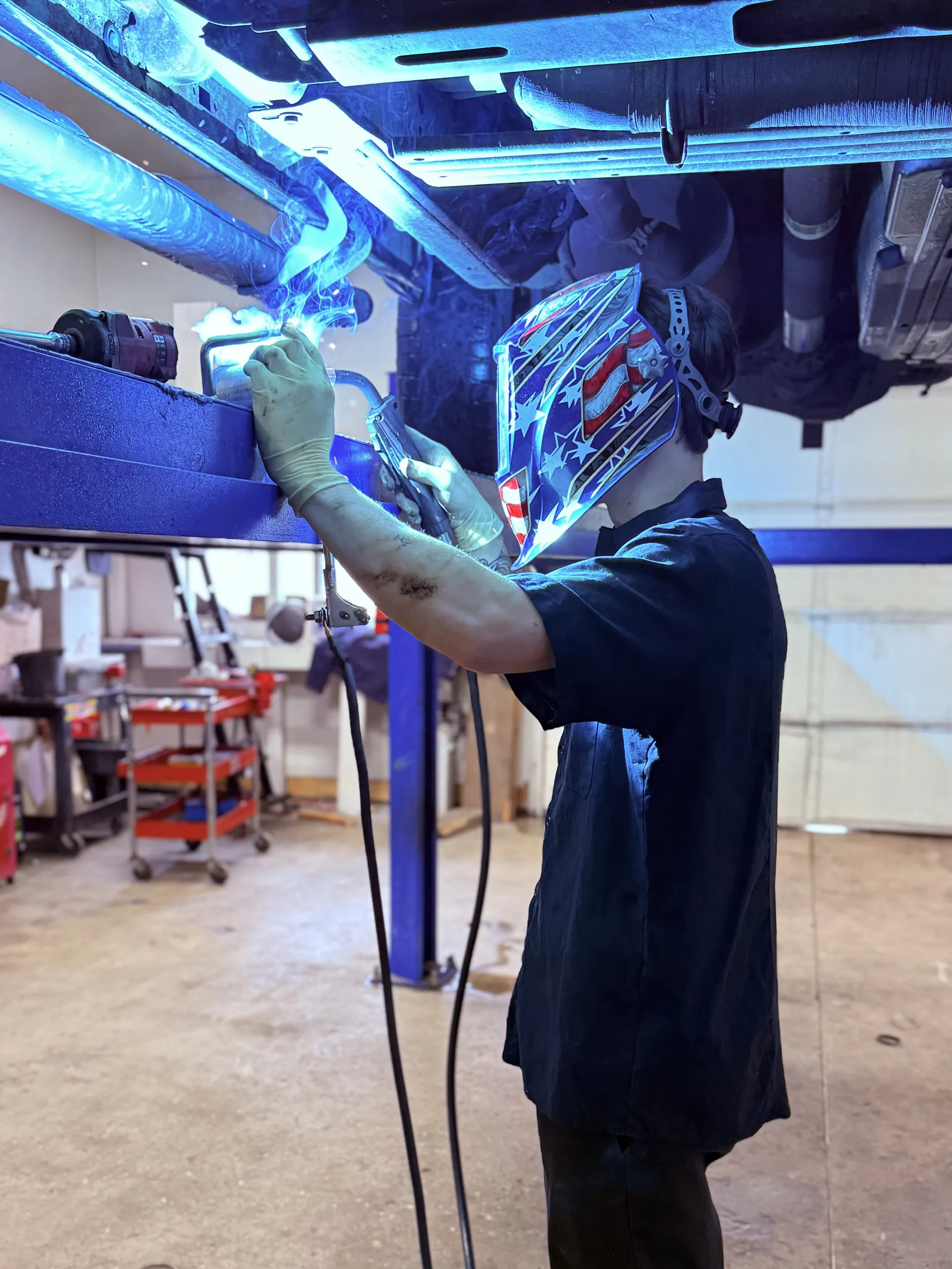 custom exhaust welding under vehicle on hydraulic lift