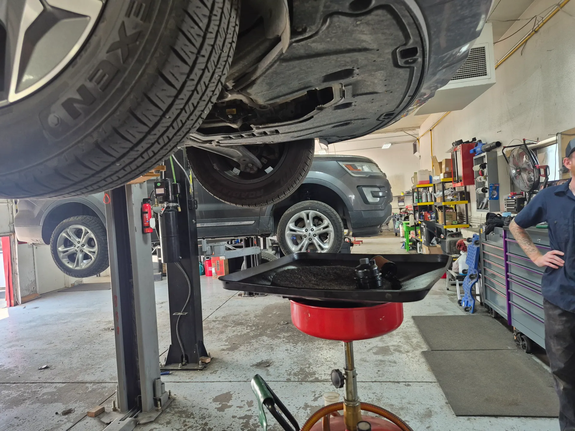 oil change service under vehicle on hydraulic lift